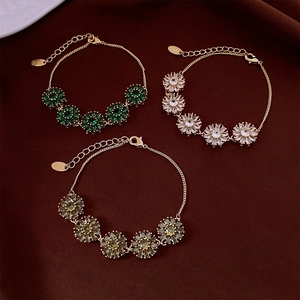 Détail macro de bracelets à fleurs plaqués or 18K avec zircons colorés sur velours rouge