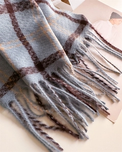 Close-up of light blue plaid scarf with brown tassels and soft faux cashmere texture