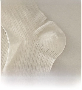 Close-up of reinforced heel detail on beige knitted crew socks with ribbed texture