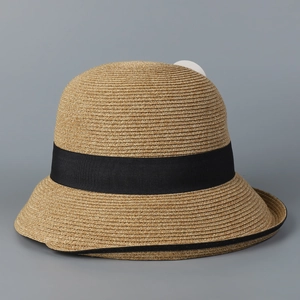 Detailed close-up of a woven straw hat featuring a black ribbon and fine edge piping