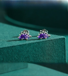 Macro detail of S925 sterling silver dinosaur earrings with purple crystal setting
