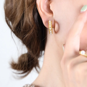 Eleganti orecchini a cerchio a C dorati con perle indossati da modella con anello abbinato