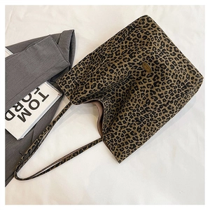 Detailed close-up of leopard print tote bag featuring a metallic oval logo and long straps