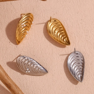 Détail de boucles d'oreilles en forme de coquillage doré et argenté avec perles