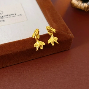 Macro de boucles d'oreilles carpe koï dorées sur un écrin à bijoux en velours marron