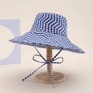 Double-sided sun hat in navy blue with white polka dots and a wide wavy brim