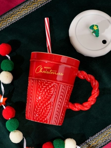 Macro detail of red ceramic Christmas mug with cable knit texture and festive straw