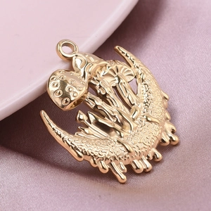 Macro view of gold stainless steel crescent moon and mushroom pendant on pink silk