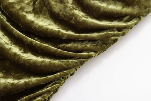 Macro shot of olive green velvet fabric showing soft texture and elegant folds