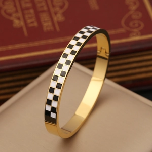 Bracciale rigido in acciaio dorato con smalto a scacchi e cuore in posa piatta professionale
