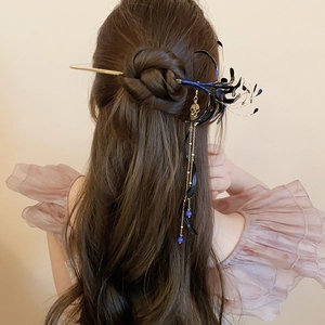 Detail of vintage blue flower tassel hair pin worn in a half-up bun hairstyle