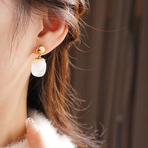 Close-up of model wearing 18K gold plated resin drop earrings with a vintage pearly finish