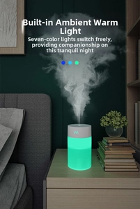 Close-up of portable USB humidifier with green LED light emitting mist on a bedside table