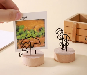 Détail de la pose d'une photo dans un pince-notes en métal avec socle en bois
