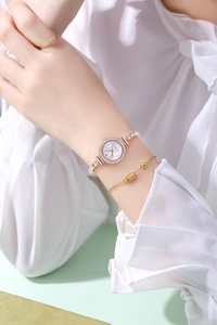 Macro view of women's quartz watch featuring rhinestone bezel and metallic beaded bracelet