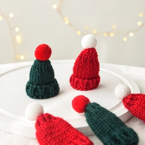 Mini knitted Christmas hats in red and green yarn with pom poms for festive decoration