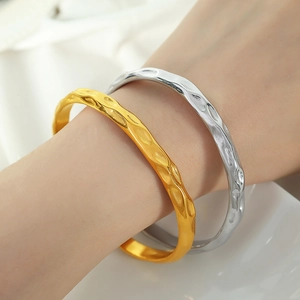Fashionable 18K gold and silver hammered titanium steel open bangles on female wrist