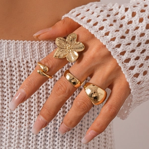 Set of four gold geometric flower rings styled on hand with an elegant metallic finish