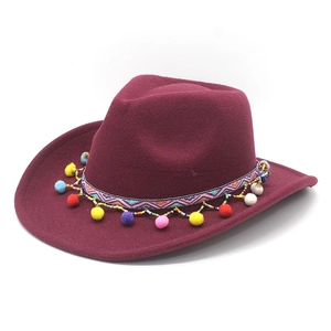 Détail du chapeau cowboy bordeaux avec ruban bohème et glands à pompons colorés