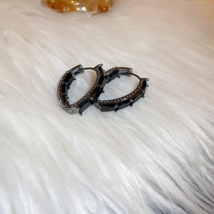 Vue détaillée des boucles d'oreilles en zircon noir sur un fond de fourrure blanche
