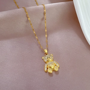 Elegant gold plated teddy bear pendant necklace with sparkling crystals on silk background