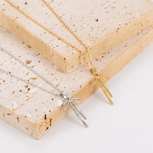 Bow pendant necklaces in gold and silver finish displayed on minimalist stone blocks