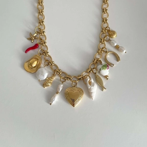 Gold charm necklace with starfish, seashell, pearl and horseshoe pendants on white background