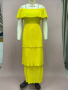 Detail eines gelben Plissee-Chiffon-Kleides mit schulterfreiem Design und Stufenrock