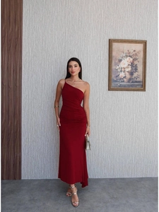 Detail of a burgundy one-shoulder bodycon dress with side ruching and asymmetrical hemline