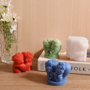 Handmade hugging couple scented candles with flower head detail on a wooden desk