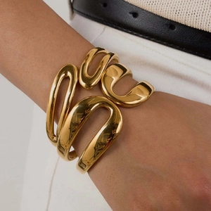Polished 18k gold plated stainless steel spring cuff bracelet with avant-garde flowing design