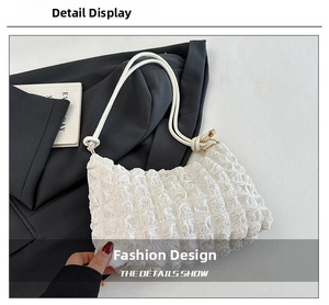 Detail of white puff bubble textured fabric and gold metal hardware on underarm bag