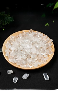 Close-up of polished clear white crystal quartz stones in a natural wood display bowl