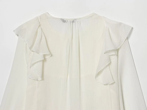 Detailed close-up of white chiffon shirt with ruffles and tiered layered shoulder design