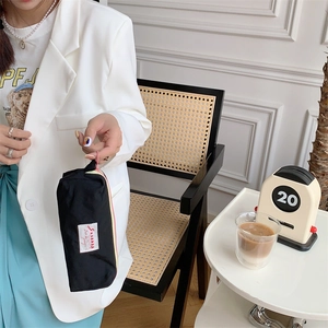 Close-up of a small black canvas storage bag held by a person in a cozy indoor setting