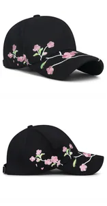 Detailed close-up of pink plum blossom embroidery on a black cotton baseball cap