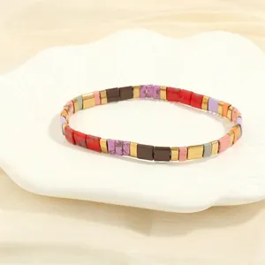 Detailed close-up of handmade Tila bead bracelet with colorful enamel and gold metal spacers