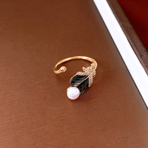 Detail of 18k gold plated feather ring featuring a white pearl and zircon leaf inlay
