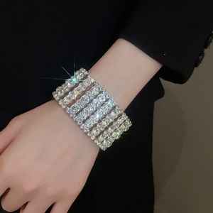 Detailed close-up of multi-row diamond-encrusted silver bracelet on a black suit sleeve