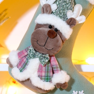 Detailed close-up of a 3D plush reindeer on a green felt Christmas stocking with warm lights