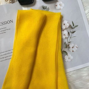 Close-up of yellow silk scarf texture on a magazine with sunglasses and dried flowers