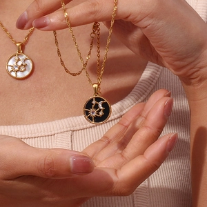 Close-up of gold-plated sun and moon necklaces with black and white zircon accents