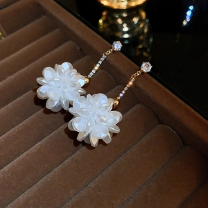 Detailed macro view of elegant white flower petal earrings with sparkling gold tassels
