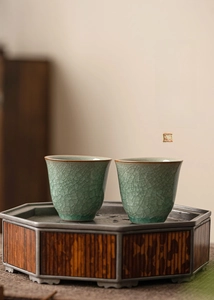 Detailed view of celadon Ru kiln teacups with ice-crack glaze on octagonal bamboo trays