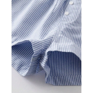 Close-up of blue and white striped shorts with button detail and fine cotton stitching