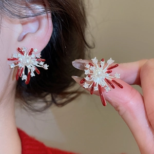 Detailed macro view of silver firework earrings with red enamel and central white pearl