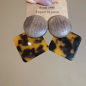 Detail view of vintage geometric earrings with wood circular top and leopard acetate pendant