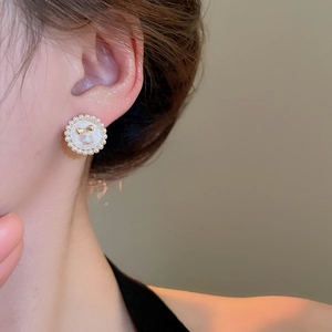 Détail d'une boucle d'oreille vintage française avec perles et nœud doré chic