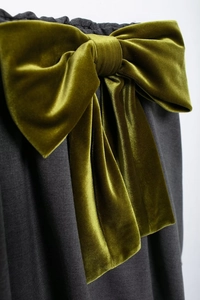 Détail d'un nœud en velours vert olive sur le tissu gris anthracite d'une mini-jupe