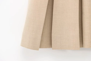 Dettaglio del vestito a pieghe kaki che mostra la trama in twill e l'orlo a strati